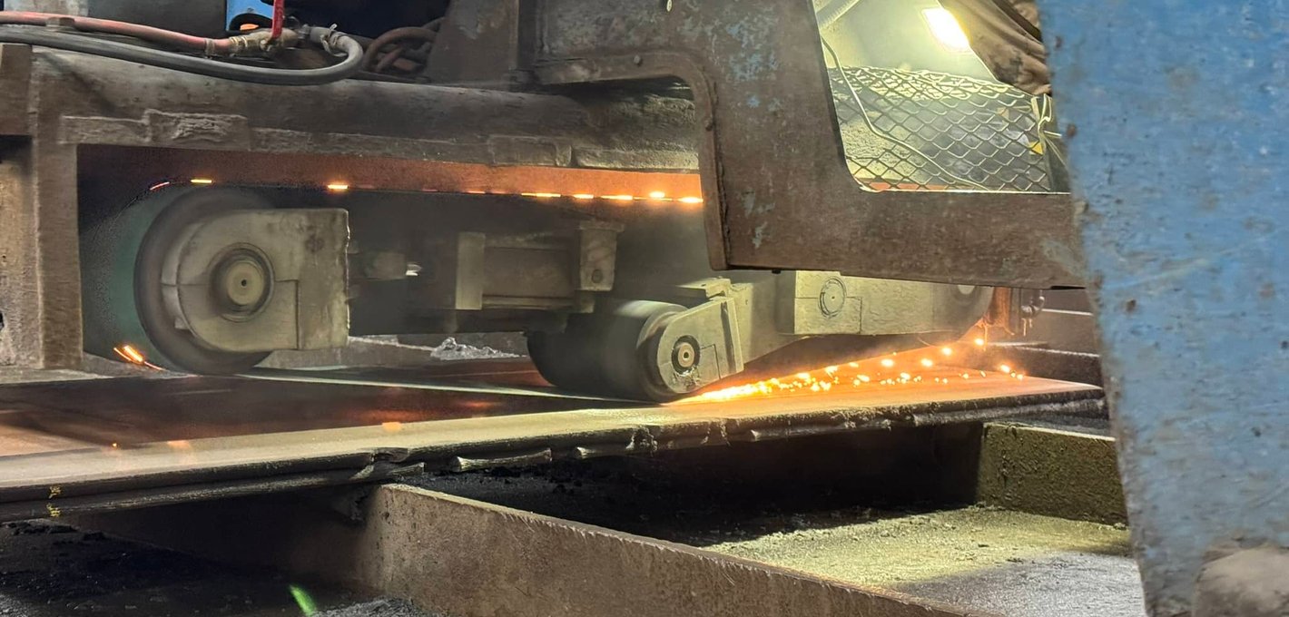 Bandsaw blade cutting through steel plate with glowing sparks