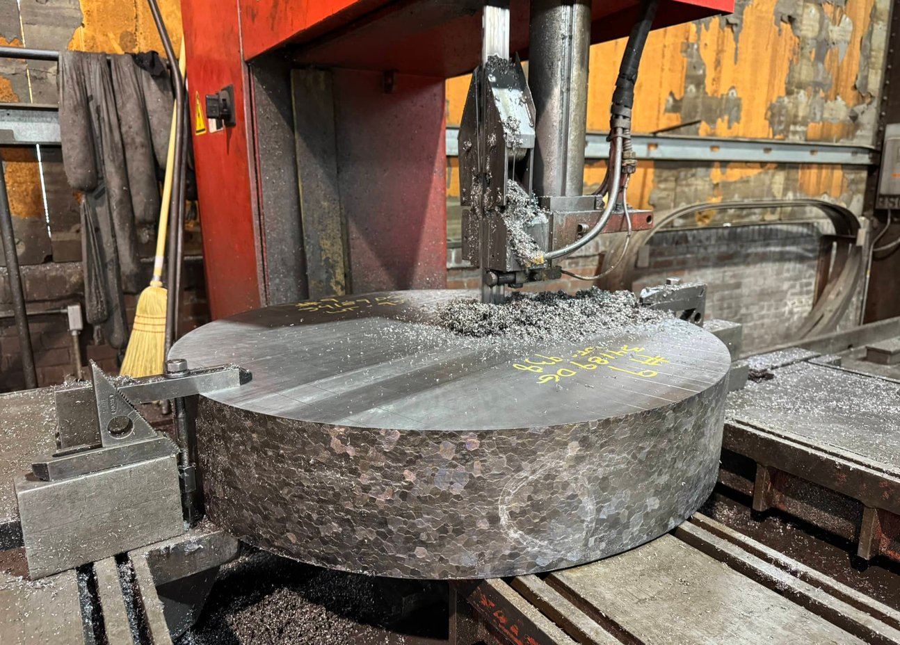 Worker operating a large Gray planer mill cutting a heavy steel block