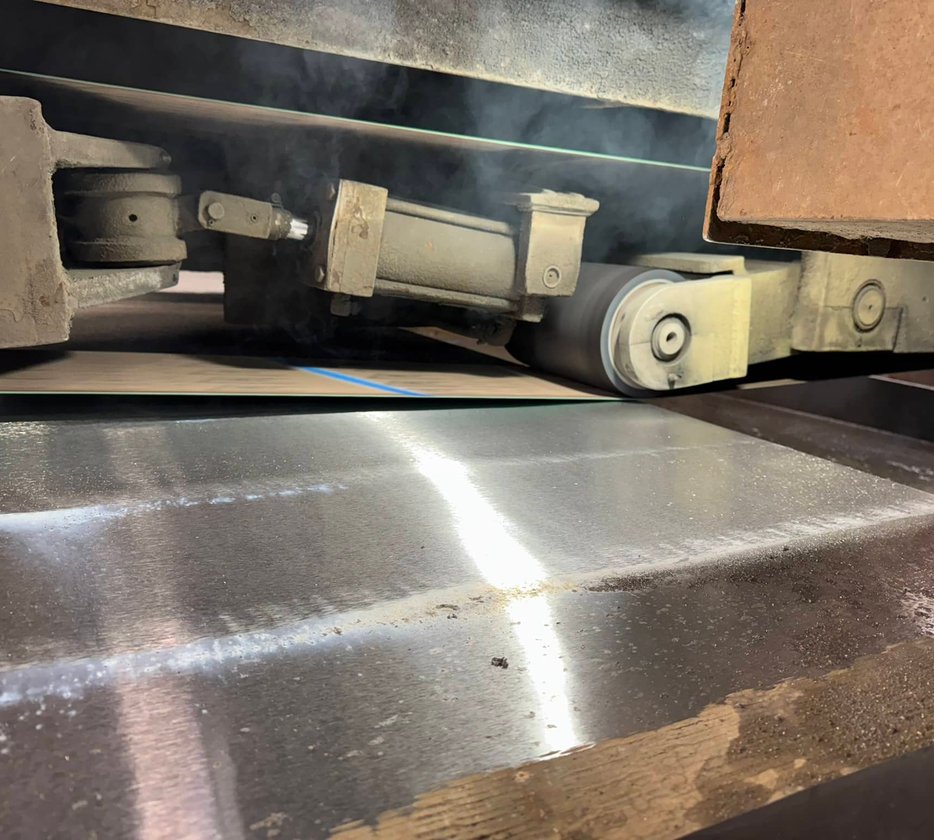 Close-up of textured steel cylinder being turned on a lathe with coolant