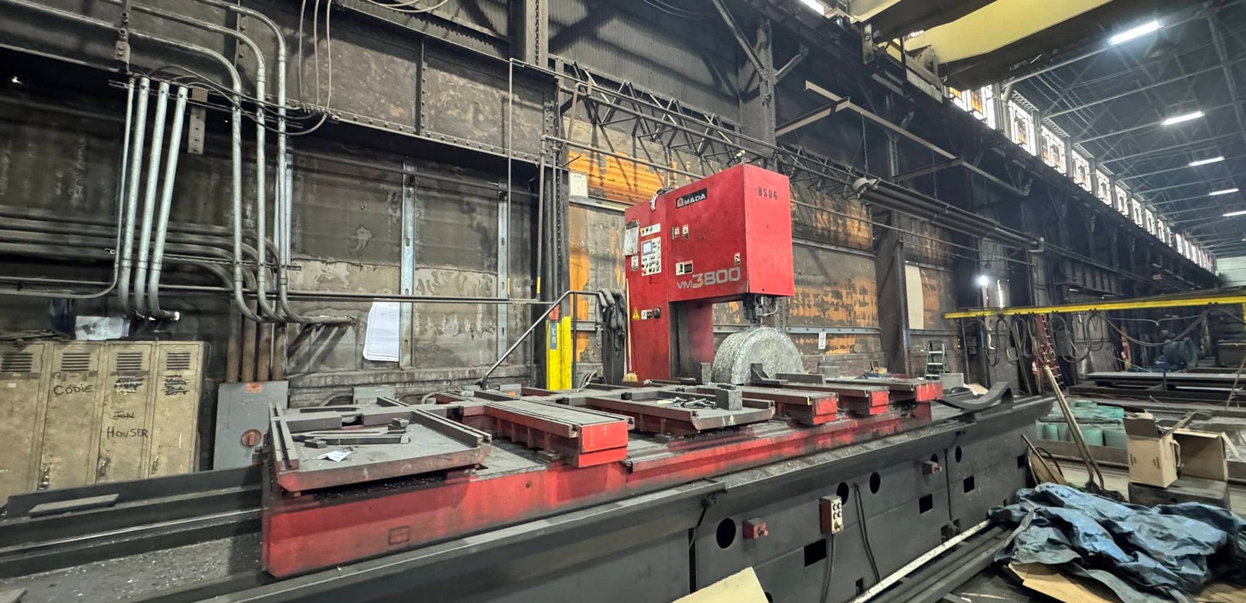 Large red Amada VM3800 bandsaw machine inside an industrial facility