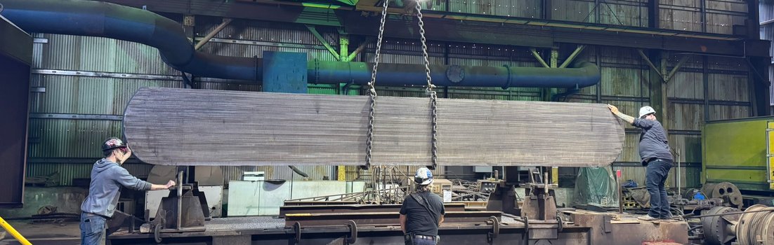 Crane loading a specialty-metal slab for wheel grinding